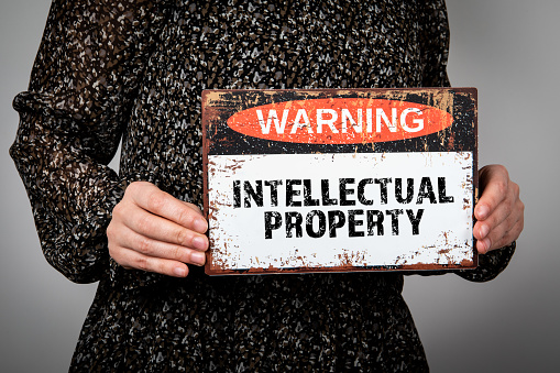 Intellectual Property. Warning sign with text in the hands of a woman.