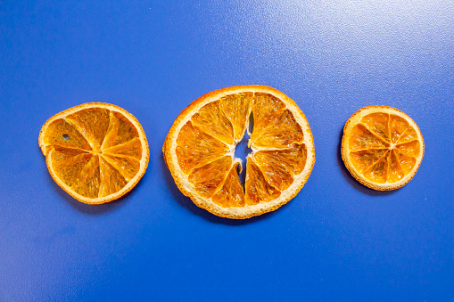 Dried orange slice on an isolated blue background. Top view, flat lay.