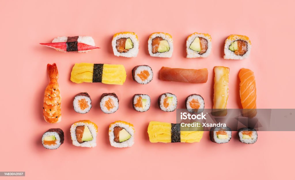 Food knolling concept - top down view of various nigiri sushi and sushi rolls on pink background Food knolling concept - flat lay of various nigiri sushi, salmon rolls on pink background. Sushi Stock Photo