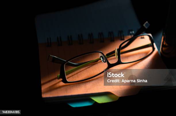 Eyeglasses On Table Above The Daily Planner Book With Sunset Shadow Background Stock Photo - Download Image Now