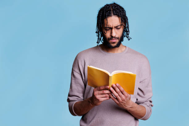istock Concentrated arab man reading paperback book with yellow cover 1483045828