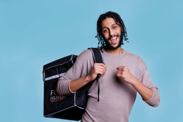 istock Cheerful food delivery service courier standing with thermal backpack 1483045965