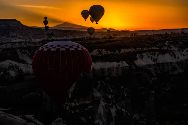 Hot Air Balloons at Love Valley in Cappadocia. Sunlight slowly illuminates Mount Erciyes. stock photo