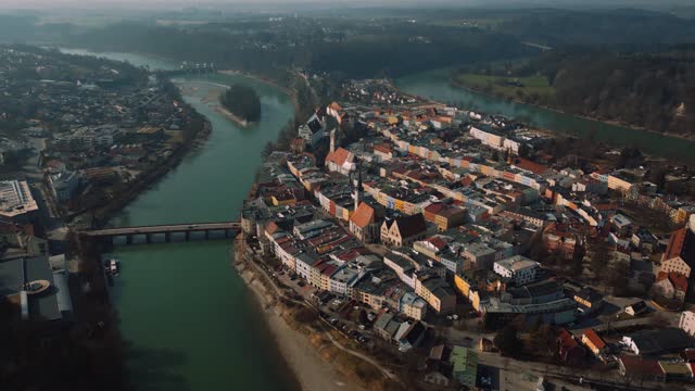 Wasserburg am Inn, an old medieval town in Bavaria, Germany, surrounded by the famous green river Inn. Aerial drone footage of old houses, a castle, bridge, church and market square in early morning fog with sunshine and sunlight. Old European city center
