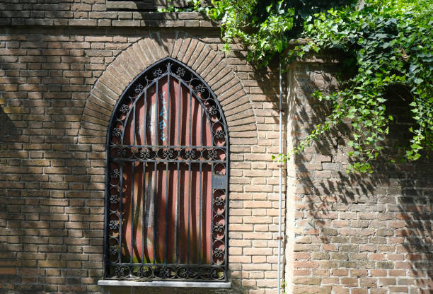 istock Closed window with shutters in the ancient brick wall. Shadows and ivy leaves on the brick wall. natural outdoor background 1483047443