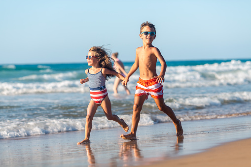 Girl and boy enjoys running on the beach on their summer vacation