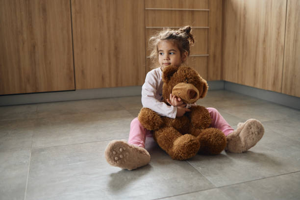 Small girl with chickenpox hugging teddy bear.