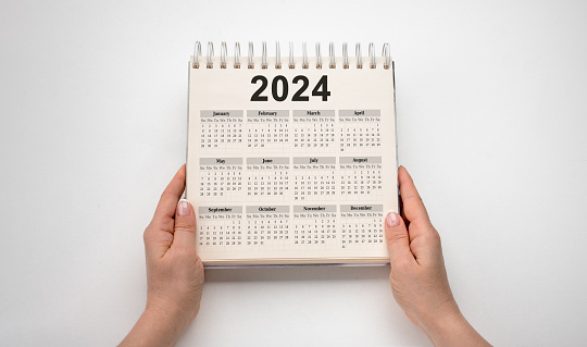 Calendar Year 2024 schedule. hands hold 2024 desk calender notepad on white background. New Year plans for 2024. goal plan, goal concept, action plan, strategy, business vision