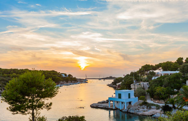 Sail Away into Paradise: A Panoramic Shot of Macarella and Macarelleta Beaches. This stunning aerial photograph captures the breathtaking beauty of Menorca's Macarella and Macarelleta bays. With the sun shining brightly and crystal-clear waters reflecting the sky, the scene exudes serenity and tranquility. The white sand beaches, surrounded by rocky cliffs and lush vegetation, provide a natural oasis for sunbathers and swimmers alike. Whether you're an avid beach-goer or simply appreciate the stunning beauty of nature, this view of Macarella and Macarelleta bays is sure to take your breath away. minorca stock pictures, royalty-free photos & images