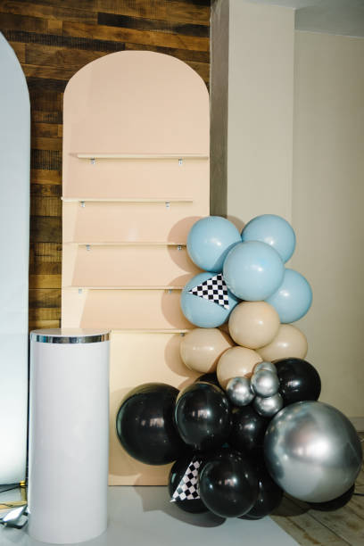 istock Trendy decor with race flag, car for boy. Birthday decorations with blue, brown, black, silver balloons for party. Arch for celebration event. Photo wall with space or place for text. Table for cake. 1483049149