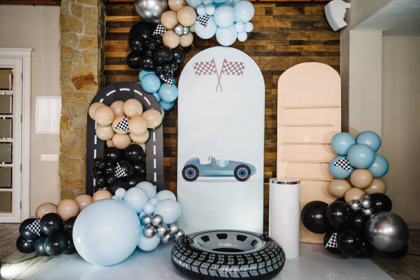 istock Birthday decorations with blue, brown, black, silver balloons for party. Arch for a celebration event. Photo wall decoration space or place for text. Trendy decor with flag, race, wheel, car for boy. 1483049157