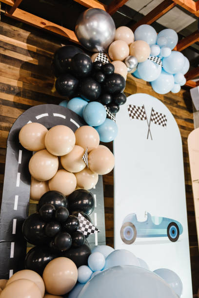 istock Birthday decorations with blue, brown, black, silver balloons for party. Arch for a celebration event. Photo wall decoration space or place for text. Trendy decor with flag, race, wheel, car for boy. 1483049159