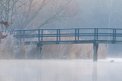 Deel van een brug over het water op een koude en mistige ochtend