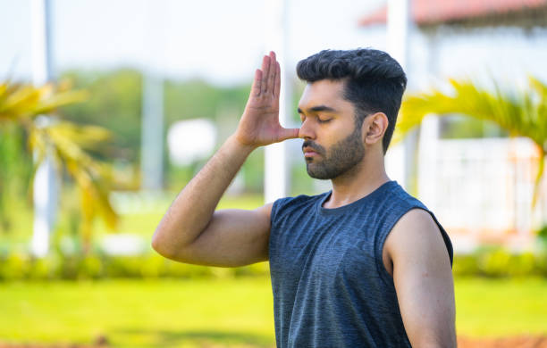 giovane che fa respirazione delle narici o pranayama yoga al parco - concetto di stile di vita sano, relax e cura di sé - pranayama foto e immagini stock