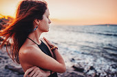 Woman at the seashore staring the sunset