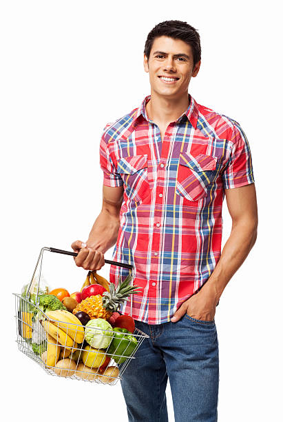 Man Carrying Basket Full Of Groceries - Isolated Portrait of handsome young man in casual wear carrying shopping basket full of groceries. Vertical shot. Isolated on white. holding shopping basket stock pictures, royalty-free photos & images