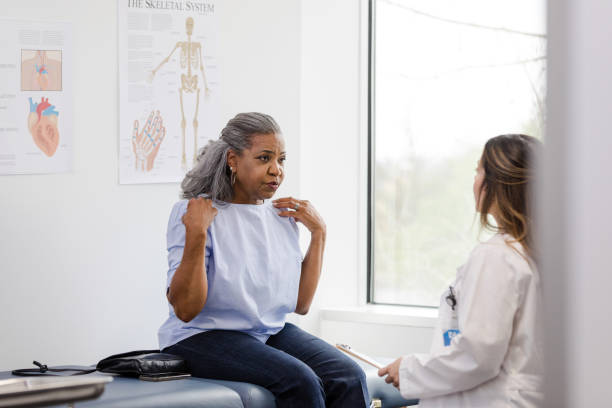 istock Mature woman gestures towards her shoulders while talking with the physical therapist 1483051994