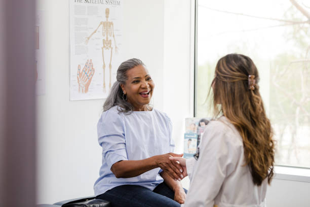 Female patient shakes hands with the female healthcare professional stock photo