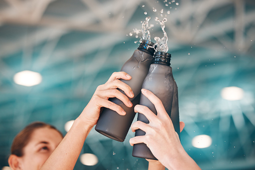 Cheers, hands and bottle water in sport celebrating victory or achievement after training, fitness or workout. Exercise, group and team winning in unity, support and teamwork with hydration