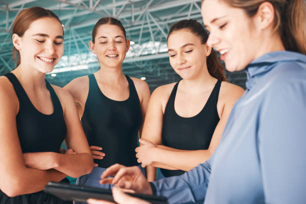 Sports coach, girls looking at tablet for training data and happy group at indoor swimming pool. Instructor showing athletes workout, young swimmers learning from teacher and performance analytics entrenador deportivo, chicas que buscan en la tableta datos de entrenamiento y grupo feliz en la piscina cubierta. instructor que muestra el entrenamiento de los atletas, los jóvenes nadadores que aprenden del profesor y el análisis de rendimiento
