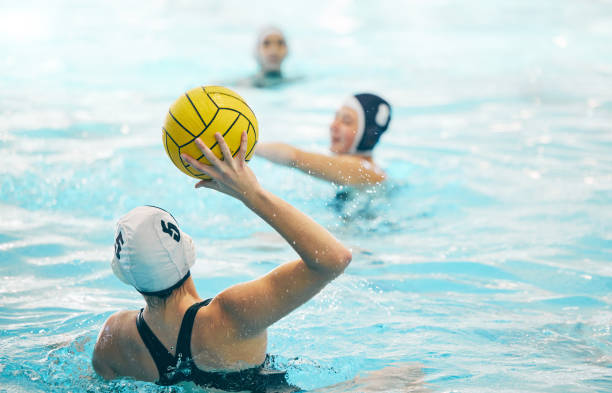 Sports, swimming pool and girl with ball for water polo for training, exercise and fitness with team. Professional sport, teamwork and female athlete focus for winning game, competition and match Sports, swimming pool and girl with ball for water polo for training, exercise and fitness with team. Professional sport, teamwork and female athlete focus for winning game, competition and match water polo cap stock pictures, royalty-free photos & images