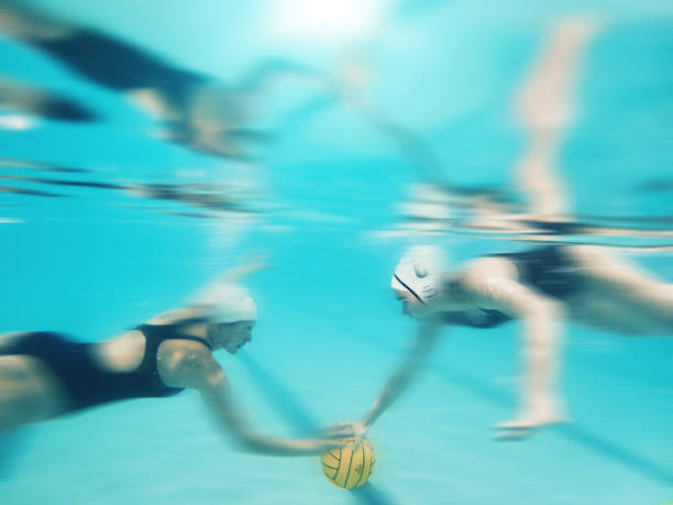 水球、スポーツ、競技、試合、水泳中にボールを水中で水中で見る女性。チームワーク、アクション、ぼやけたアスリートチームがチャンピオンシップのプールでプロの試合をする - 水球 ストックフォトと画像