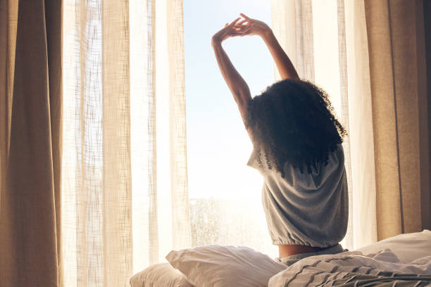 istock Black woman, back stretching and waking up in home bedroom after sleeping or resting. Relax, peace and comfort of female stretch after feeling fresh, awake and well rested to start morning in bed. 1483052149