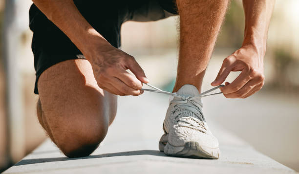 istock Fitness, shoes and laces with a man runner getting ready for a cardio or endurance workout closeup outdoor. Exercise, running and workout with a male athlete fastening shoelaces while training 1483052174