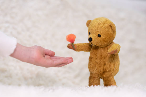 istock A teddy bear presenting a flower and a child's hand receiving it 1483053393