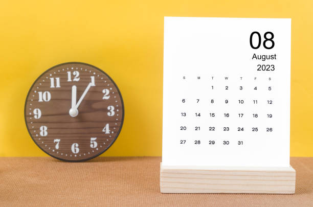The August 2023 Monthly calendar for 2023 year  with clock on yellow table. stock photo