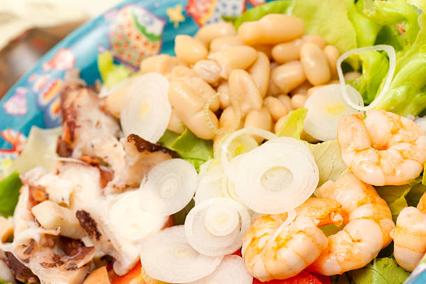 Shrimps with salad on a white plate. Closeup.