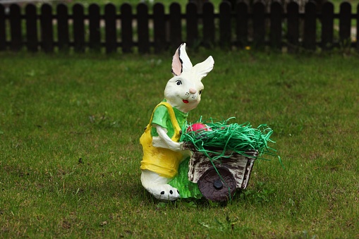 Decorative bunny pushing a cart, a fence in the background and green grass