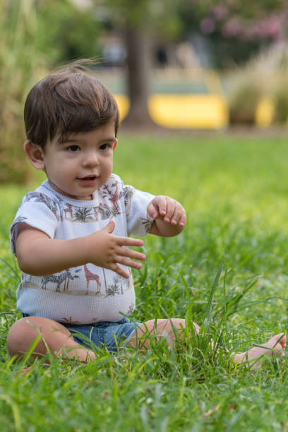 istock Little baby boy playing sitting on the grass in the park. 1483058991
