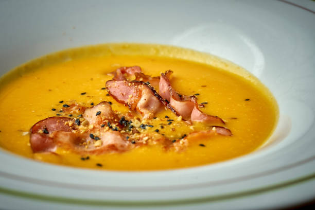 Pumpkin cream soup with bacon in a plate on a wooden background stock photo