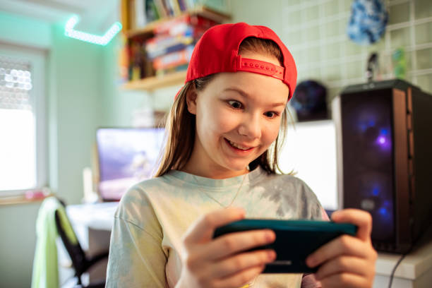 istock Young girl playing games on her smart phone in her bedroom by the desktop computer 1483060455