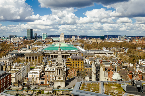 High angle view depicting the futuristic, modern towers and skyscrapers that constitute the economic and financial heart of the city of London. These buildings are interspersed with historic, ancient architecture of yesteryear. Numerous cranes fill the scene, as they construct the next wave of architecture in the heart of the city.