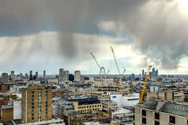 High angle view depicting the futuristic, modern towers and skyscrapers that constitute the economic and financial heart of the city of London. These buildings are interspersed with historic, ancient architecture of yesteryear. Numerous cranes fill the scene, as they construct the next wave of architecture in the heart of the city.