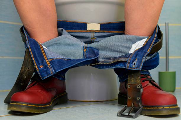 A man sitting on the toilet. A concept from the 1980s. Red punk shoes and jeans. Gender theme and urban culture. stock photo