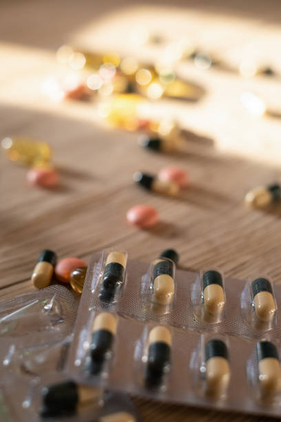 istock Flat lay composition with a bunch of different colorful pills scattered on the table from a plastic bottle. Heap of opened medicines on wooden table textured background 1483066683