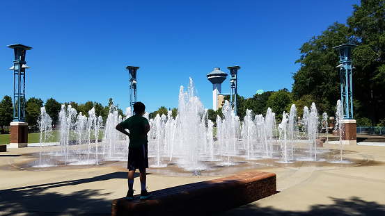 Boy looking at fountain before deciding to play in the water, River Heritage Park, Florence, Alabama