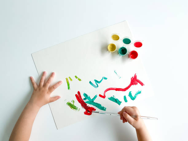istock small child draws with paints and brush on white table. fathers day 1483067245