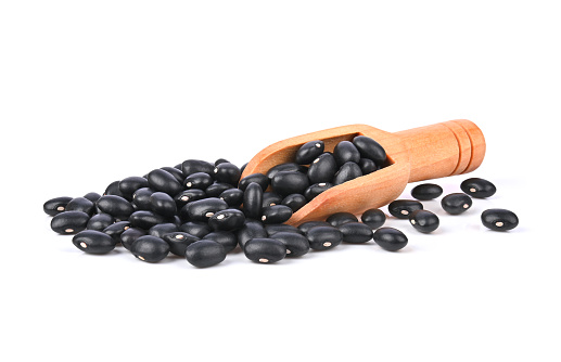 Black beans (black lentil, black gram, vigna mungo ) and wooden scoop isolated on white background