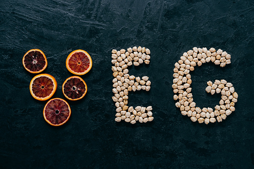 Food letters. Garbanzo and slice of citrus fruit in form of veg letters on dark background. Organic ingredients for vegetarians. Healthy products