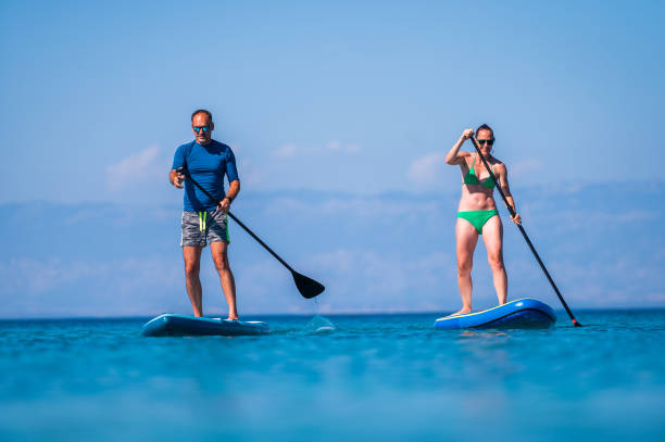 istock Couple riding SUP stand up paddle on vacation. 1483077242