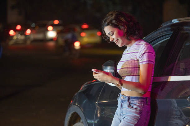 istock Happy woman leaning on car and using mobile phone 1483079777