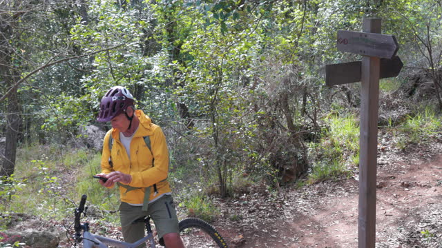 Senior man e-mountain bikes along forest path