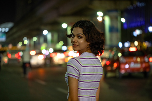 Portrait of smiling woman walking on street at night