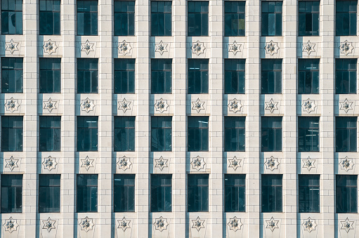 Windows in an office building with a decorative stone facade. The from of a building on the waterfront of the river thames by London Bridge.