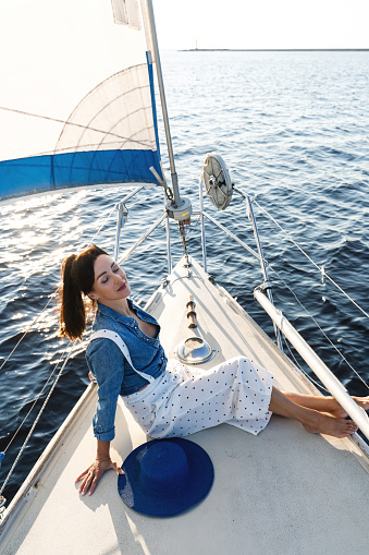 Portrait of attractive woman relaxing on sailboat during sailing in sea