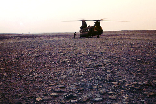 A crew member from the 101st Airborne Division monitors the engines on a CH-47D Chinook helicopter as it cranks up at dusk at an FOB (forward operating base) in northern Saudi Arabia on the border with Iraq just days before the start of the ground war phase of the Persian Gulf War in 1991.